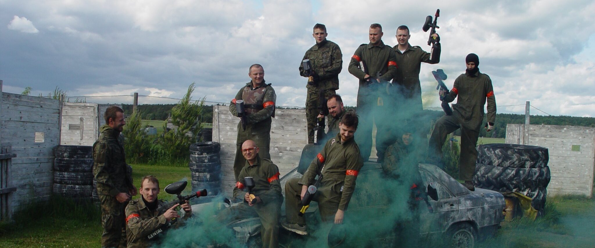 Grupa paintballowa w strojach moro w tle flara dymna.