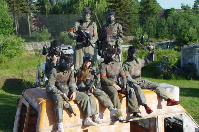 Grupa paintballowa siedząca na samochodzie dostawczym.