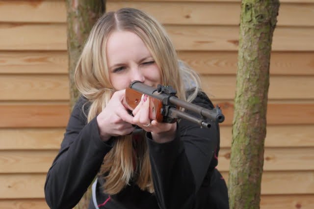 Kobieta korzysta ze strzelnicy - celuje do tarczy.