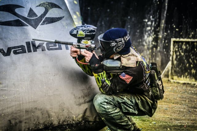 Gracz paintballowy chowa się za dmuchaną przeszkodą