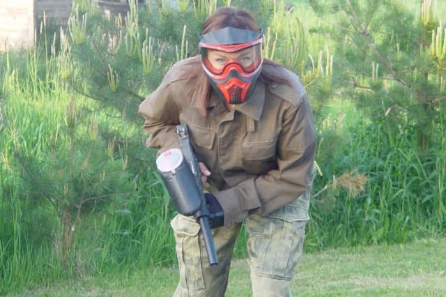 Wieczór panieński - kobieta w czerwonej masce paintballowej w trakcie gry.