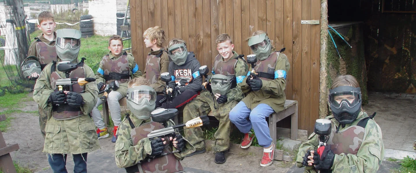 Grupa dzieci w strojach do paintballa.
