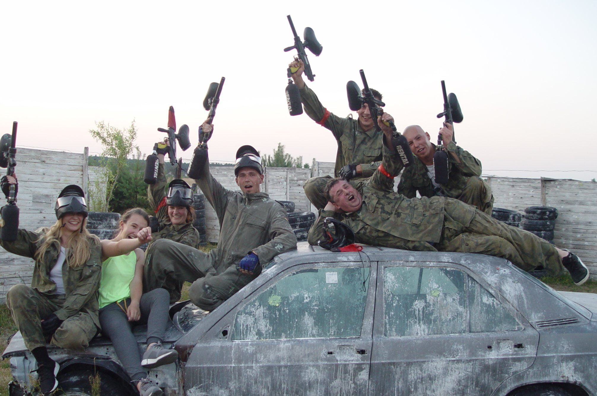 Paintball na imprezie firmowej - zadowolona grupa siedząca na samochodzie po grze.